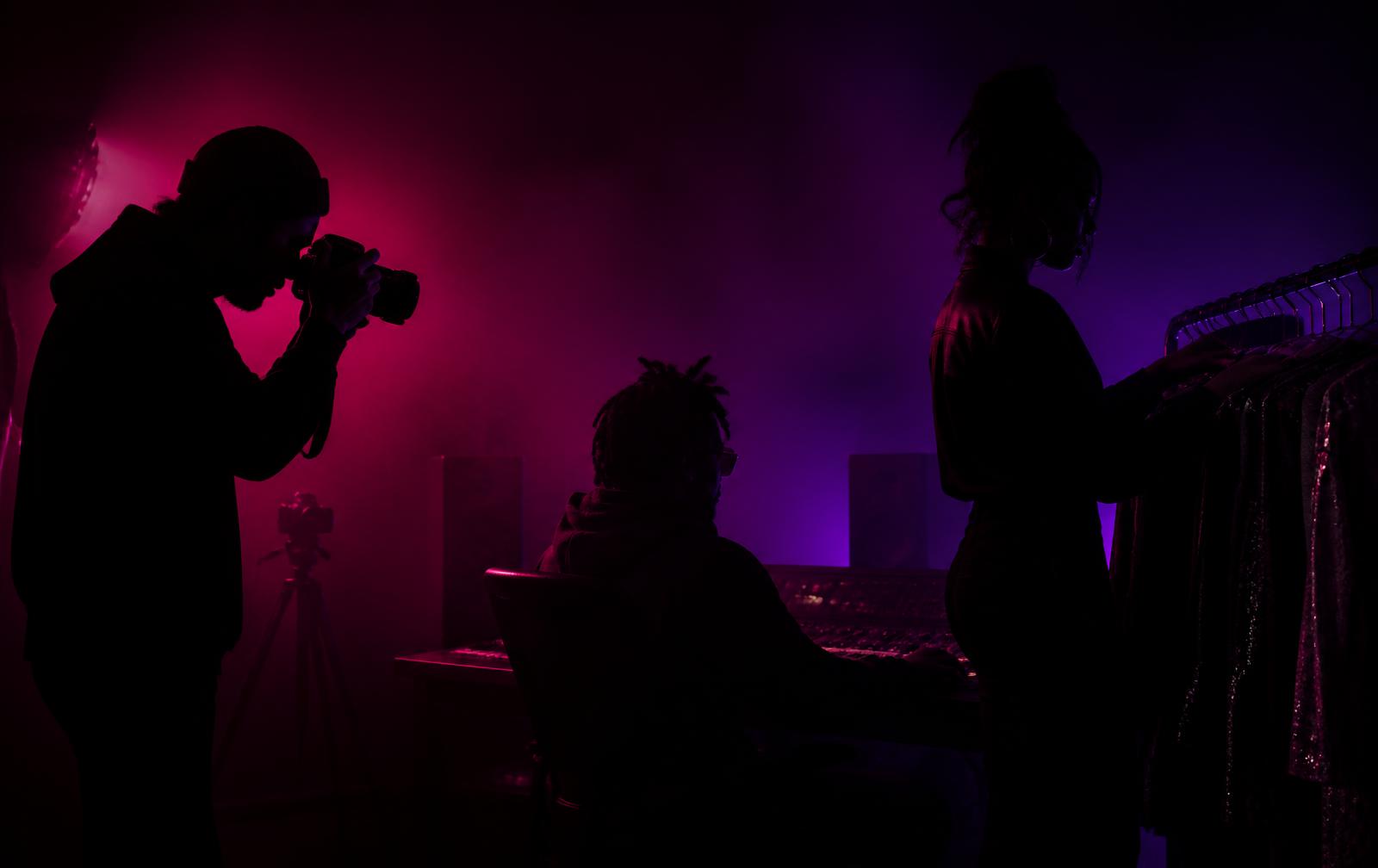 Creative professionals working under magenta and purple studio lighting